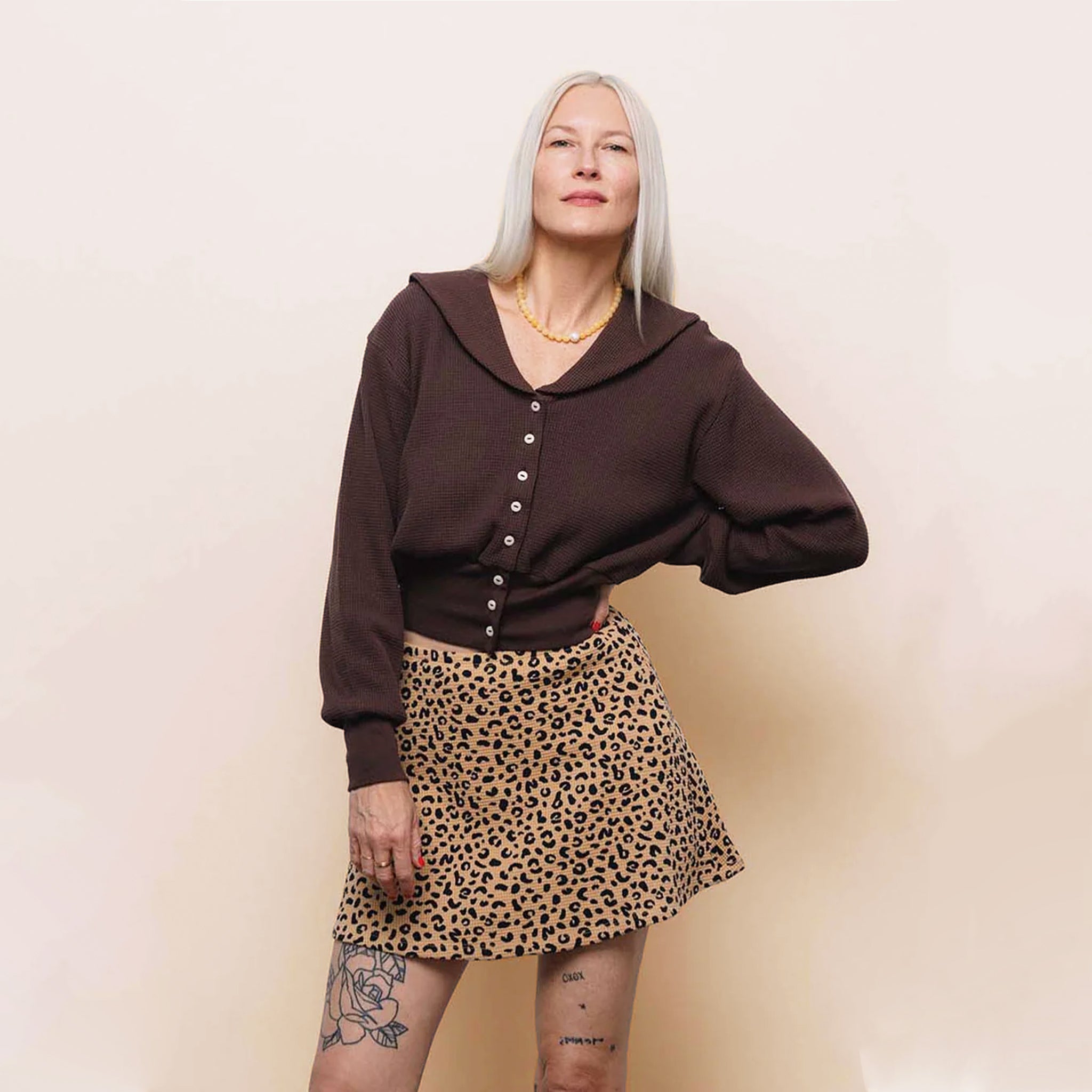 Person wearing a brown blouse and leopard print skirt against a plain background