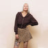 Person wearing a brown blouse and leopard print skirt against a plain background