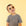 On a light yellow background is a children's model wearing a yellow round pair of sunglasses. 