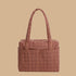 A tan and rust colored printed nylon carry on bag.