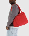 A red small carry on tote bag with two handle straps, front pockets and a zipper closure.