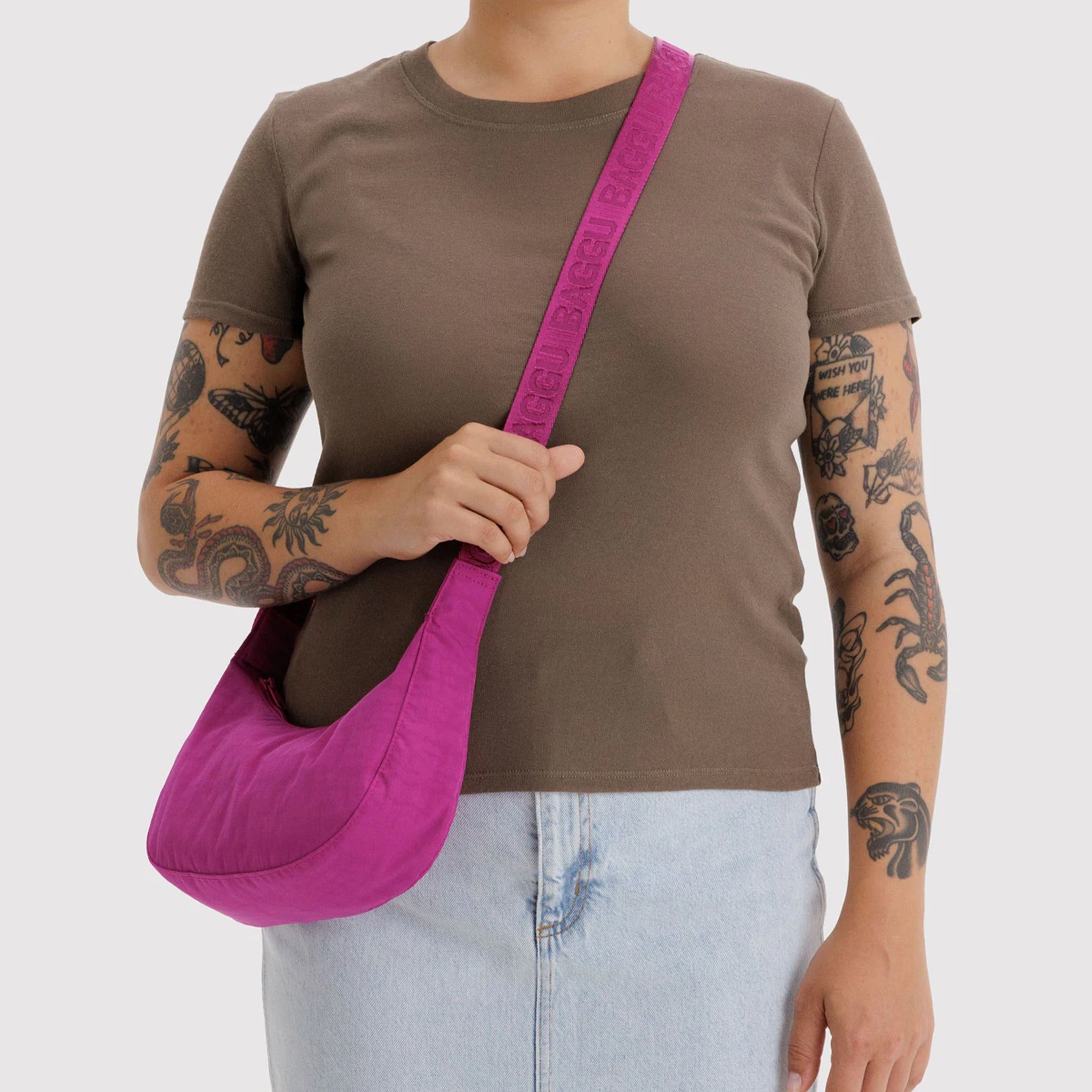 A hot pink crescent shaped nylon handbag. 