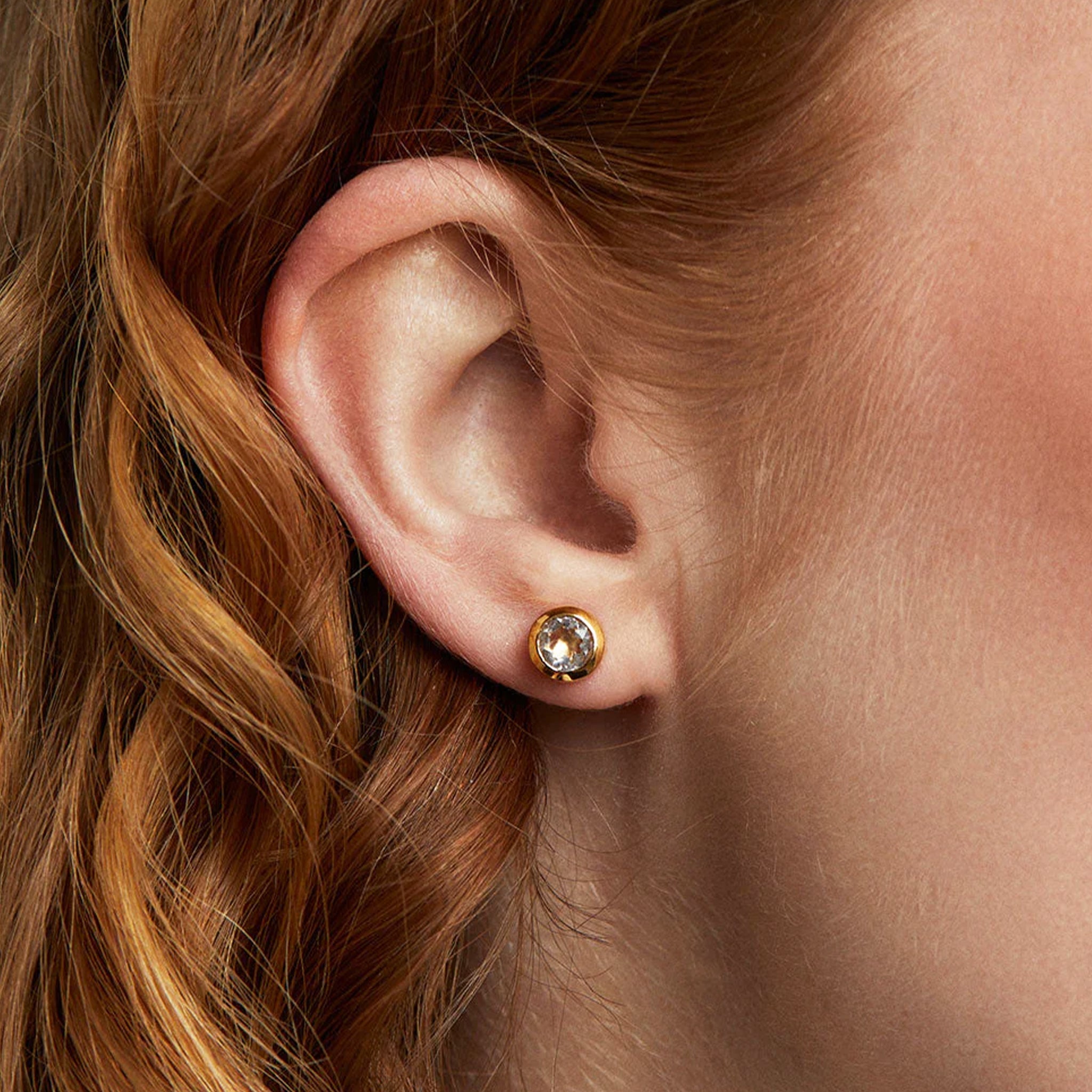 A pair of gold circle stud earrings with crystal cz stones in the center. 