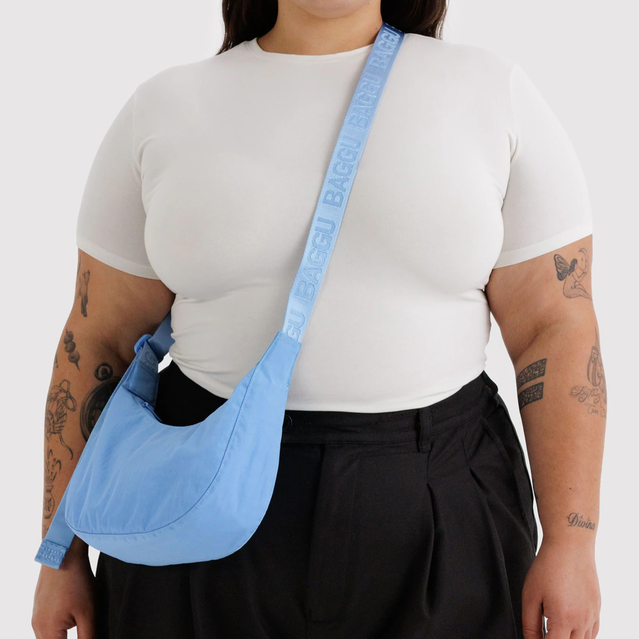 A blue nylon crossbody bag on a model.