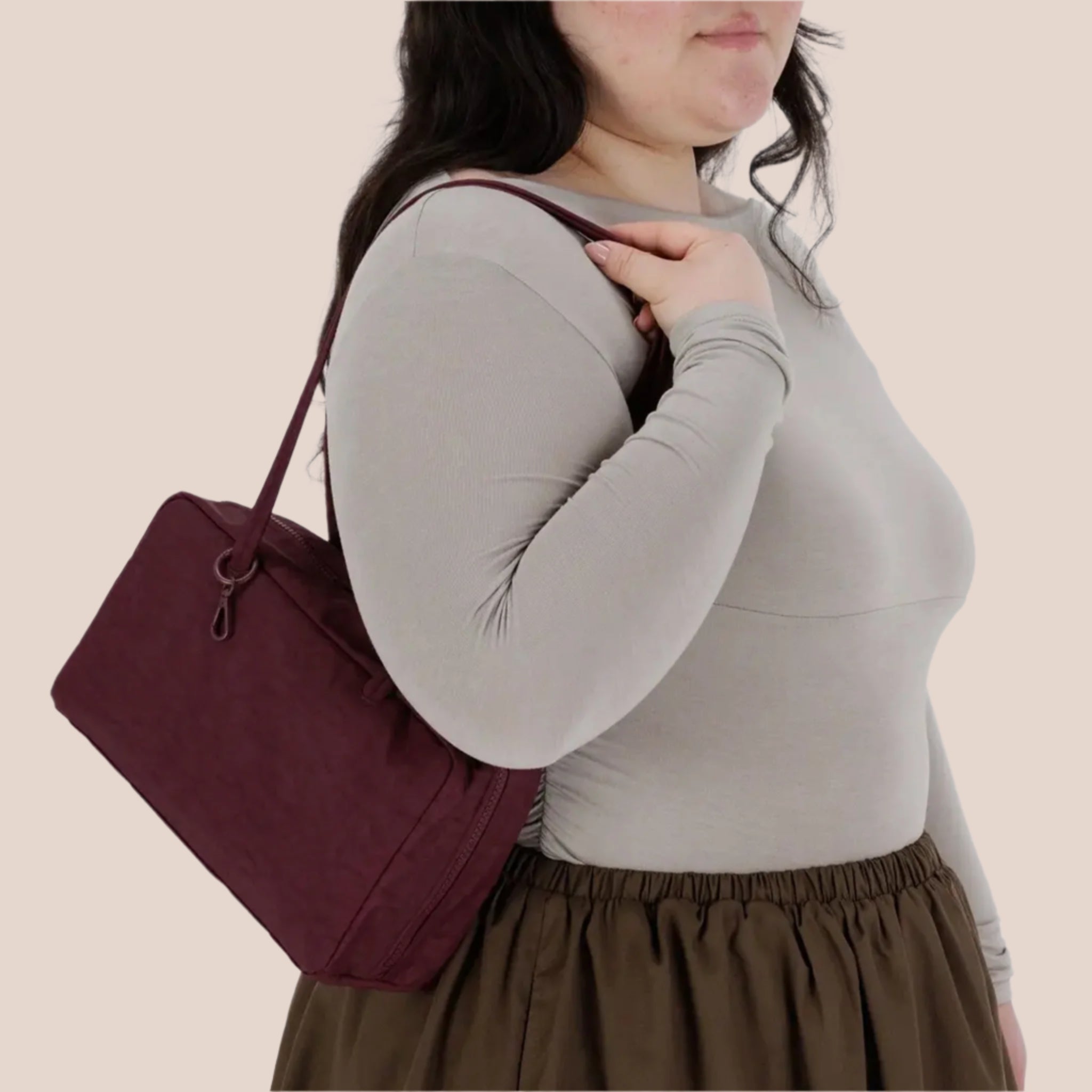 A mahogany reddish brown colored nylon handbag with a large shoulder strap. 