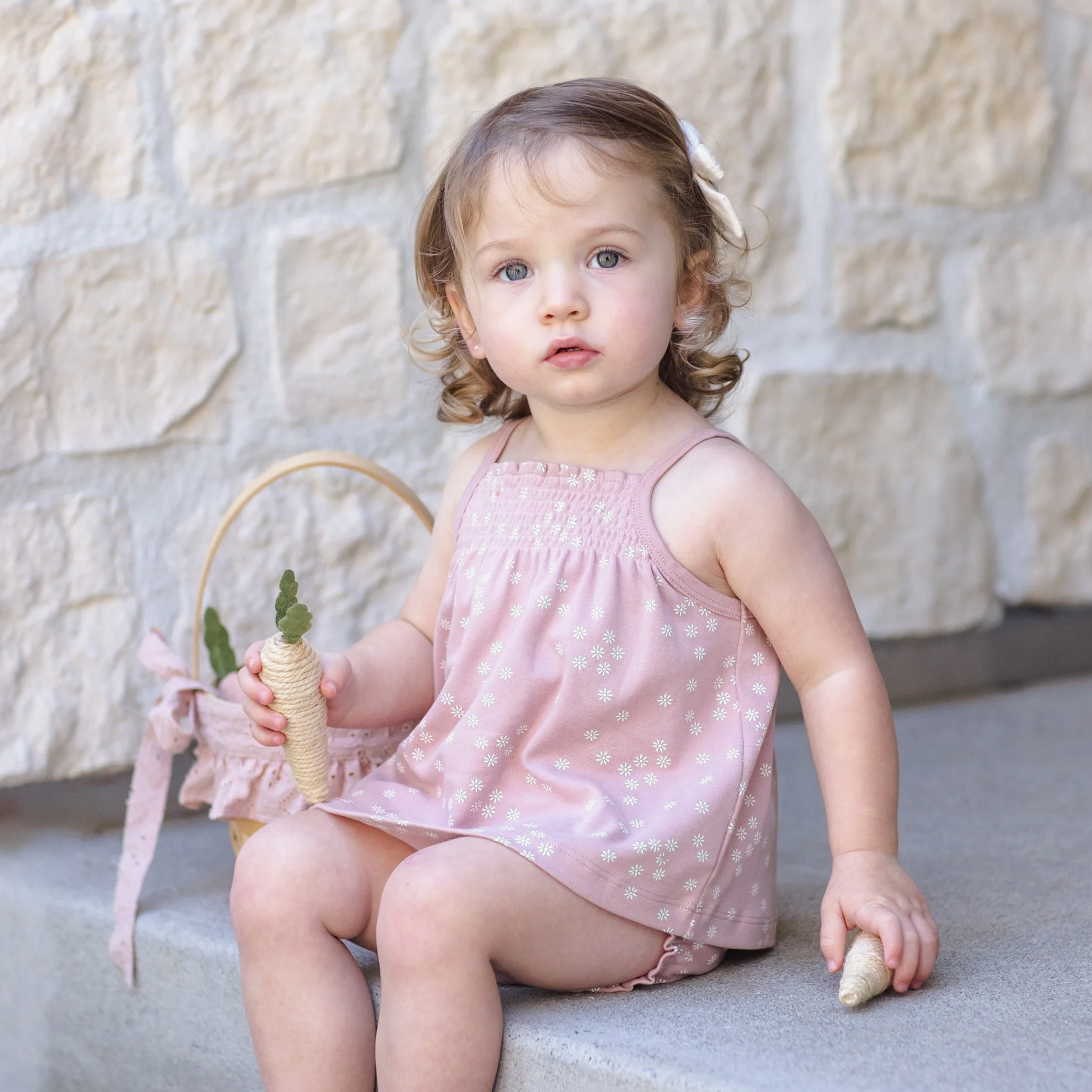 A light pink tank top and bloomer set with a white daisy print. 
