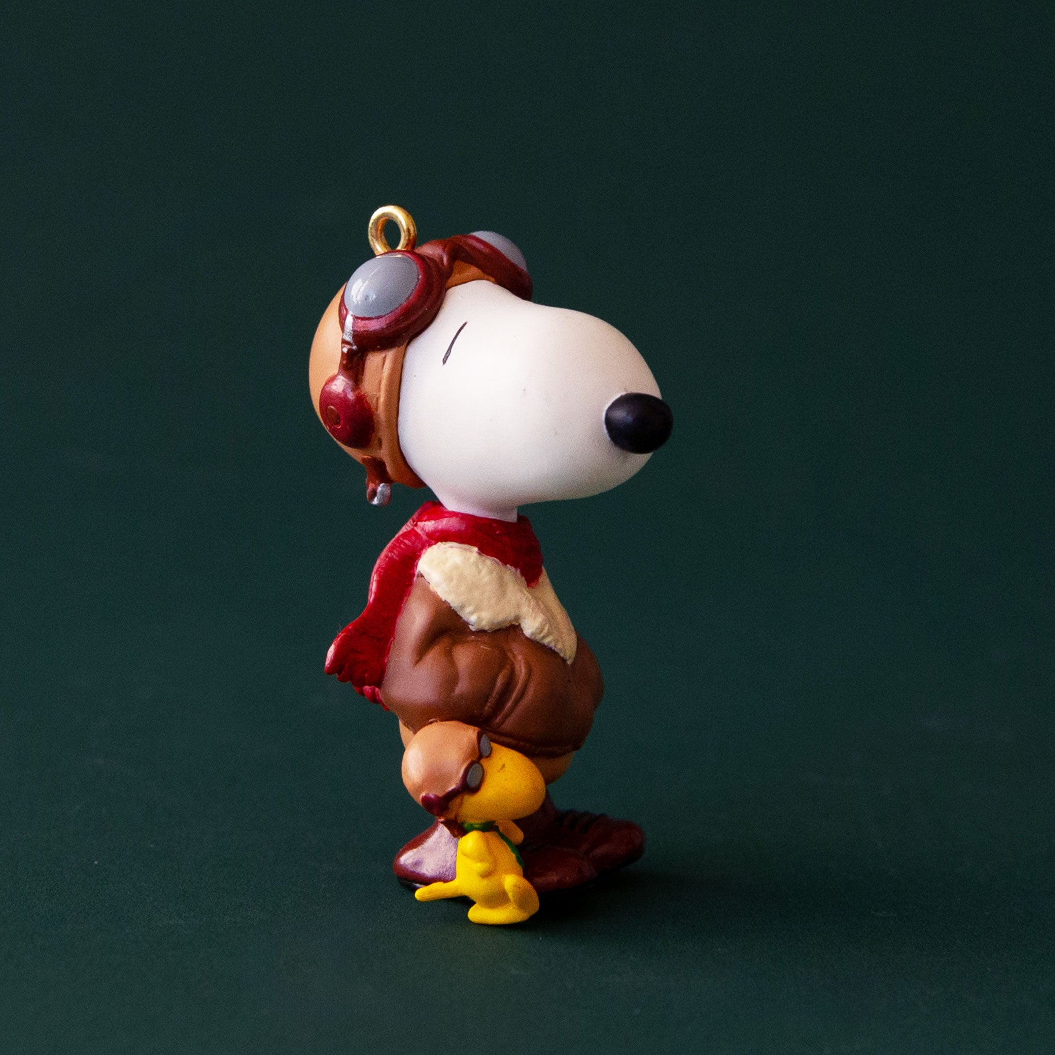 A snoopy shaped ornament wearing a pilot outfit. 