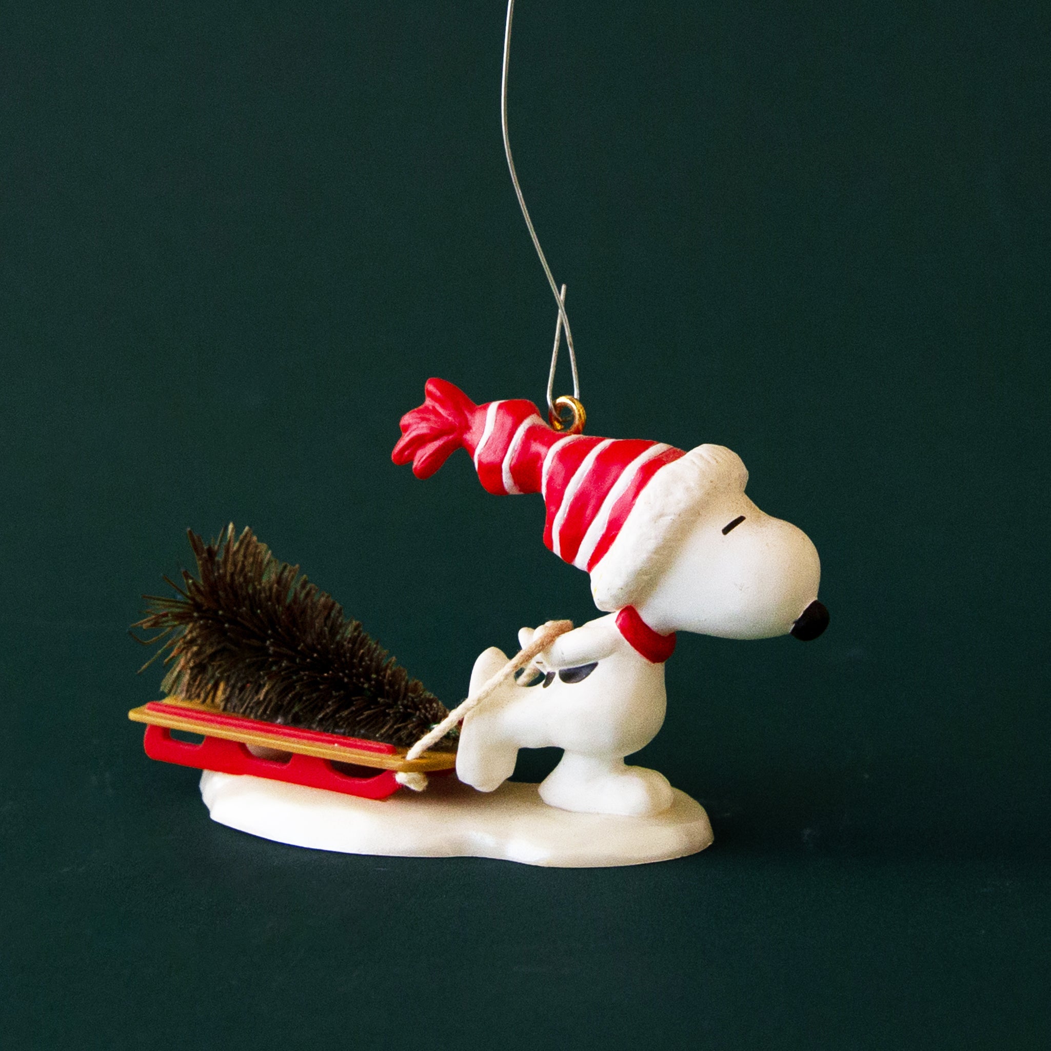 A vintage Snoopy ornament with him pulling a sled with a Christmas tree. 