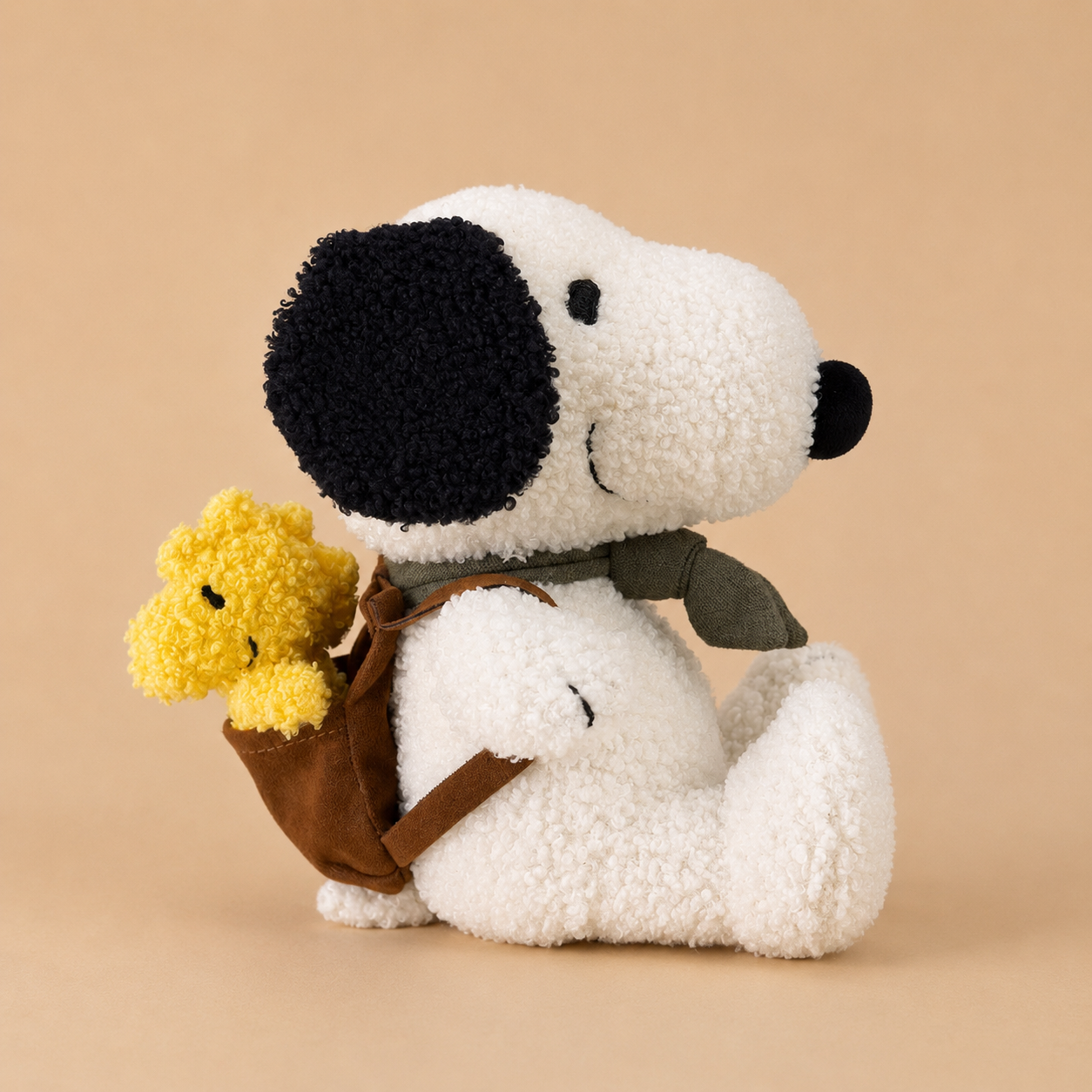 a snoopy stuffed toy with a backpack holding the character woodstock. 