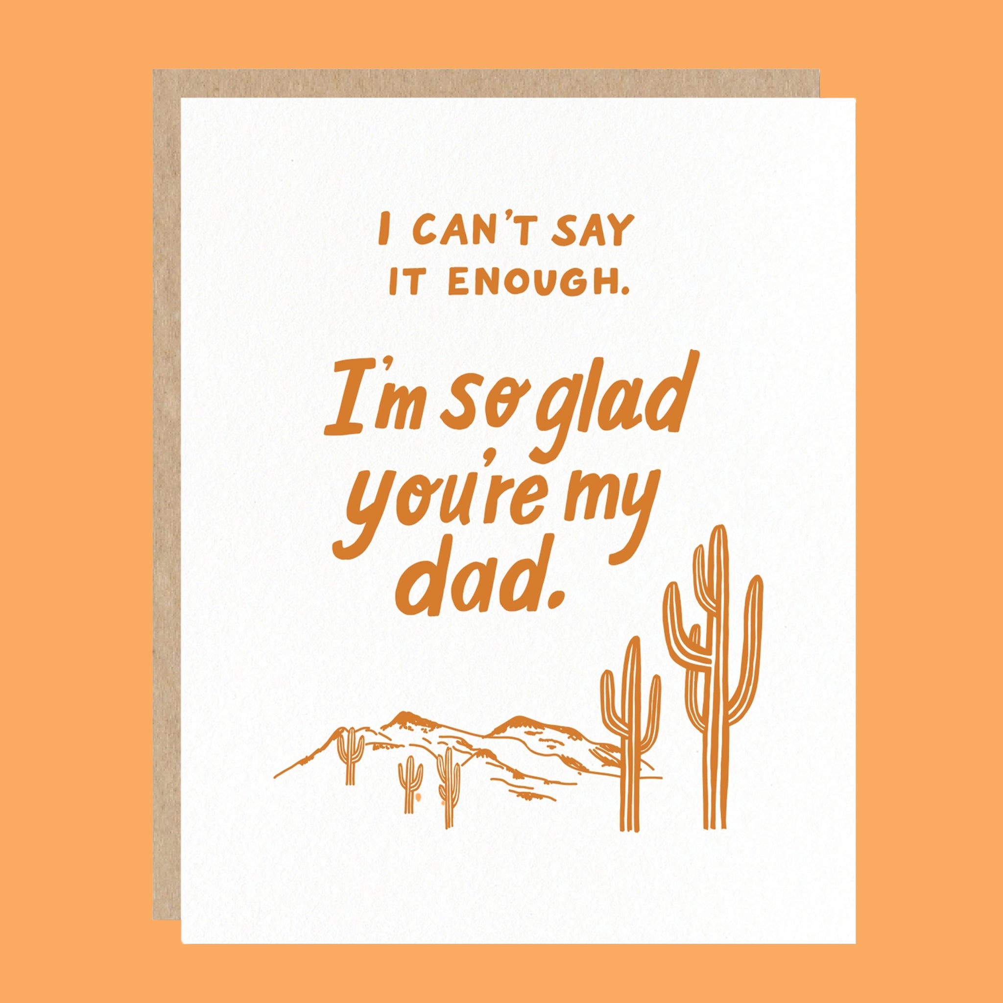On an orange background is a white card with text on the front that reads, "I Can't Say Enough. I'm so glad you're my dad." along with an illustration of desert mountains and cacti. 