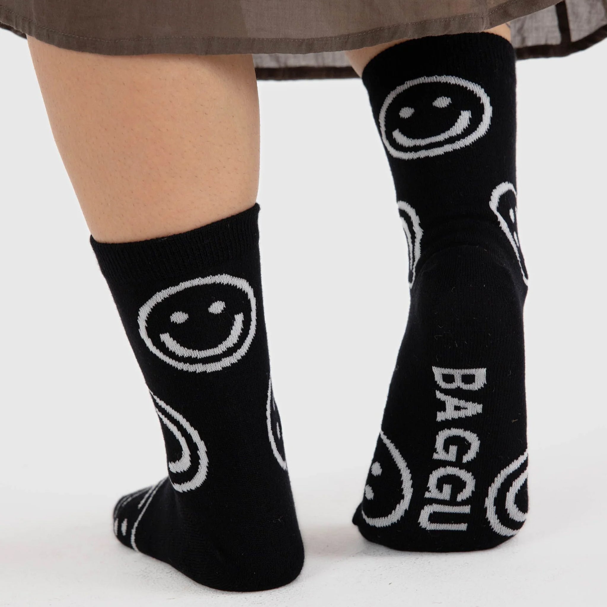 A pair of black socks with white smiley faces on them.