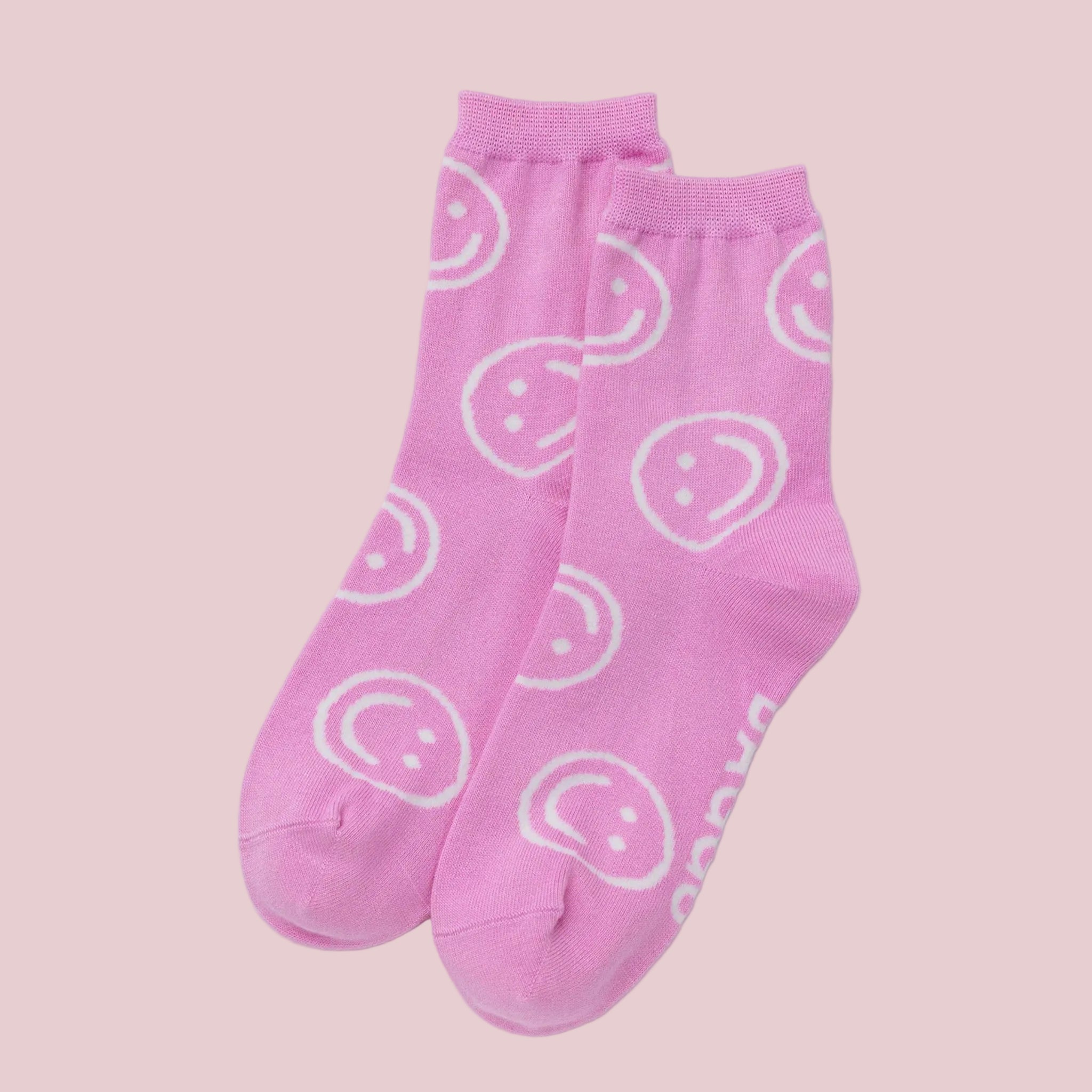 a pair of pink crew socks with smiley faces.