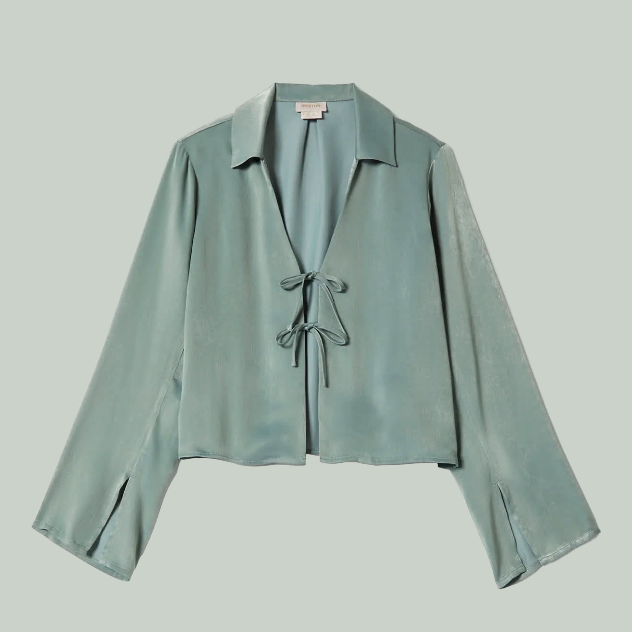 A bluish green silk long sleeve shirt with ties in the center. 