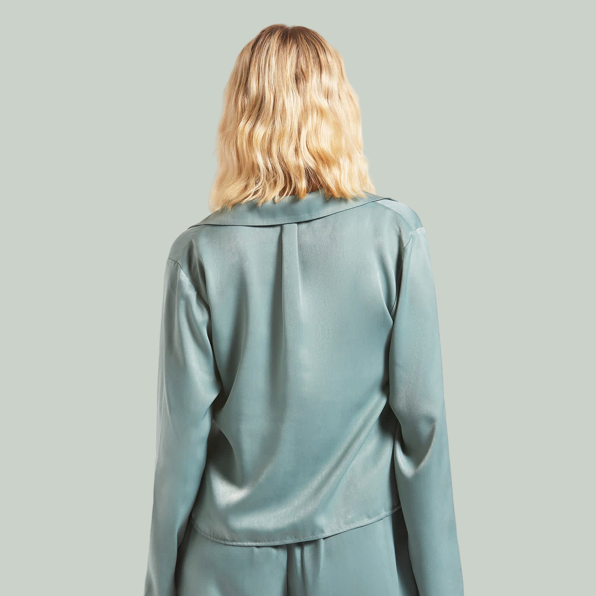 A bluish green silk long sleeve shirt with ties in the center. 