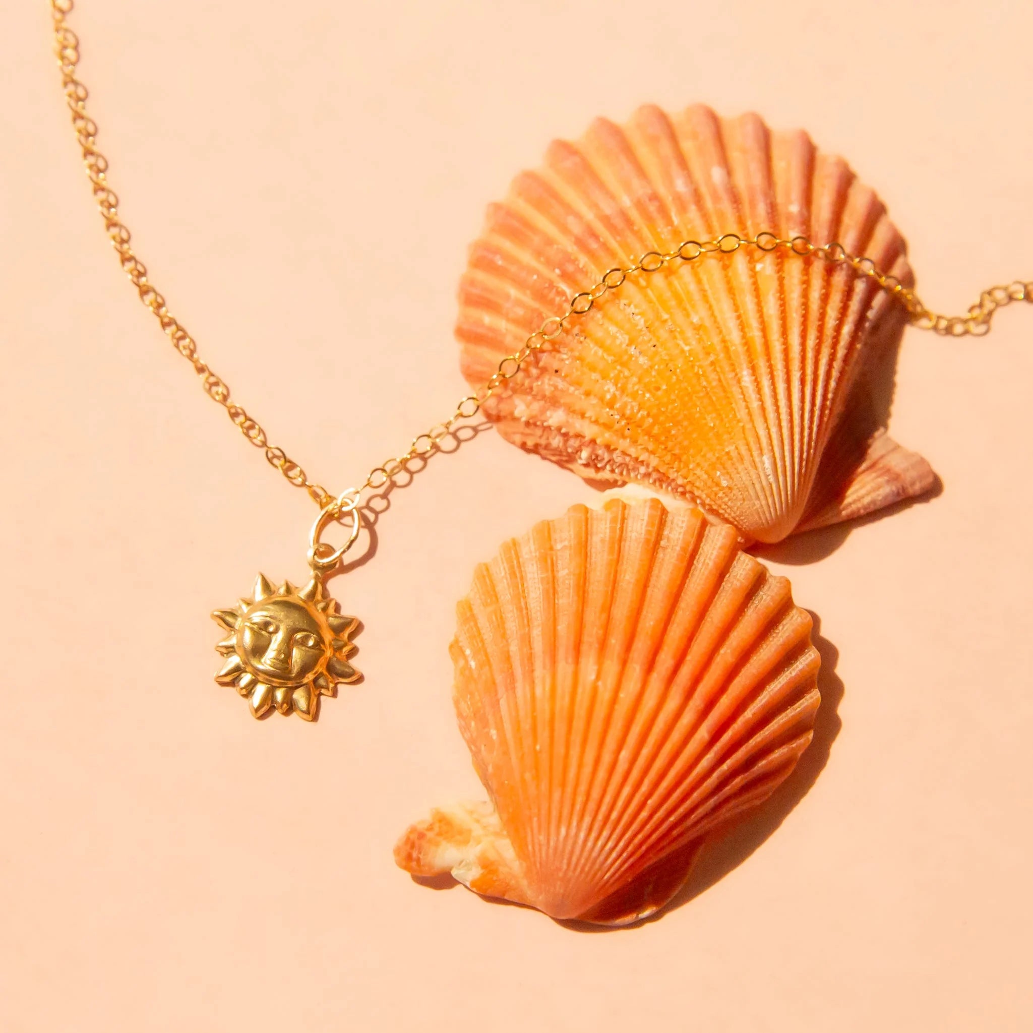 A gold chain necklace with a sun shaped pendant. 
