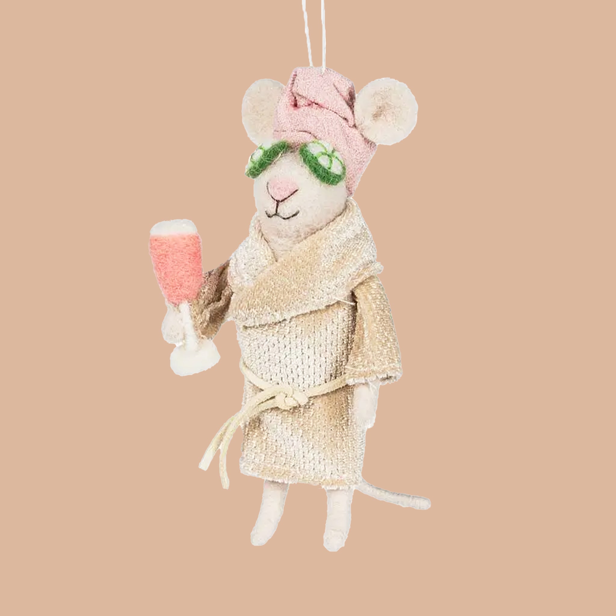 A white mouse ornament with cucumbers on its eyes and holding a drink. 