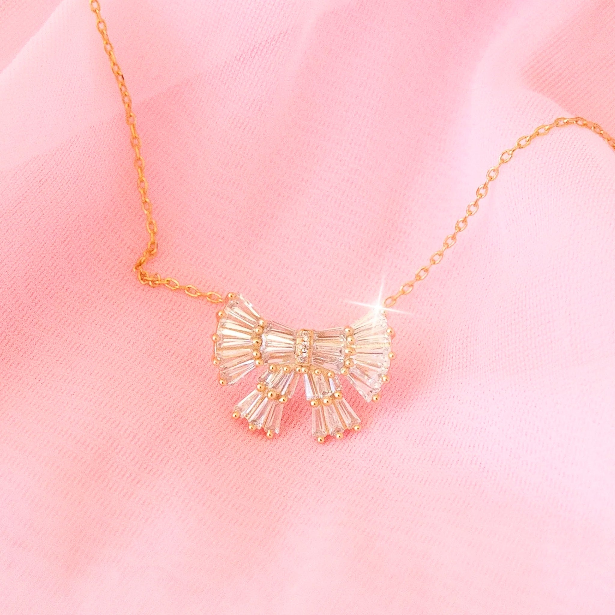CZ baguette bow necklace with gold detailing.