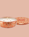 A round orange tin candle with three wicks and text on the lid that reads, 'Voluspa Spiced Pumpkin Latte'. 