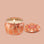 An orange wavy designed tin candle with a lid that reads, 'Voluspa Spiced Pumpkin Latte'. 