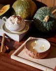 A round orange tin candle with three wicks and text on the lid that reads, 'Voluspa Spiced Pumpkin Latte'. 