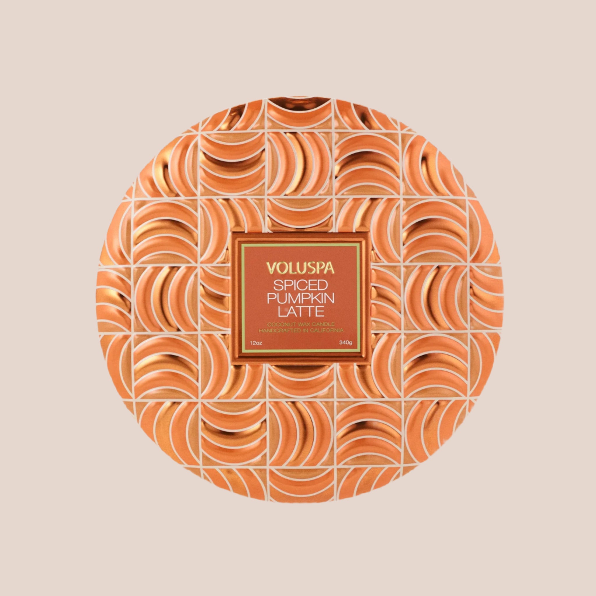 A round orange tin candle with three wicks and text on the lid that reads, &#39;Voluspa Spiced Pumpkin Latte&#39;. 