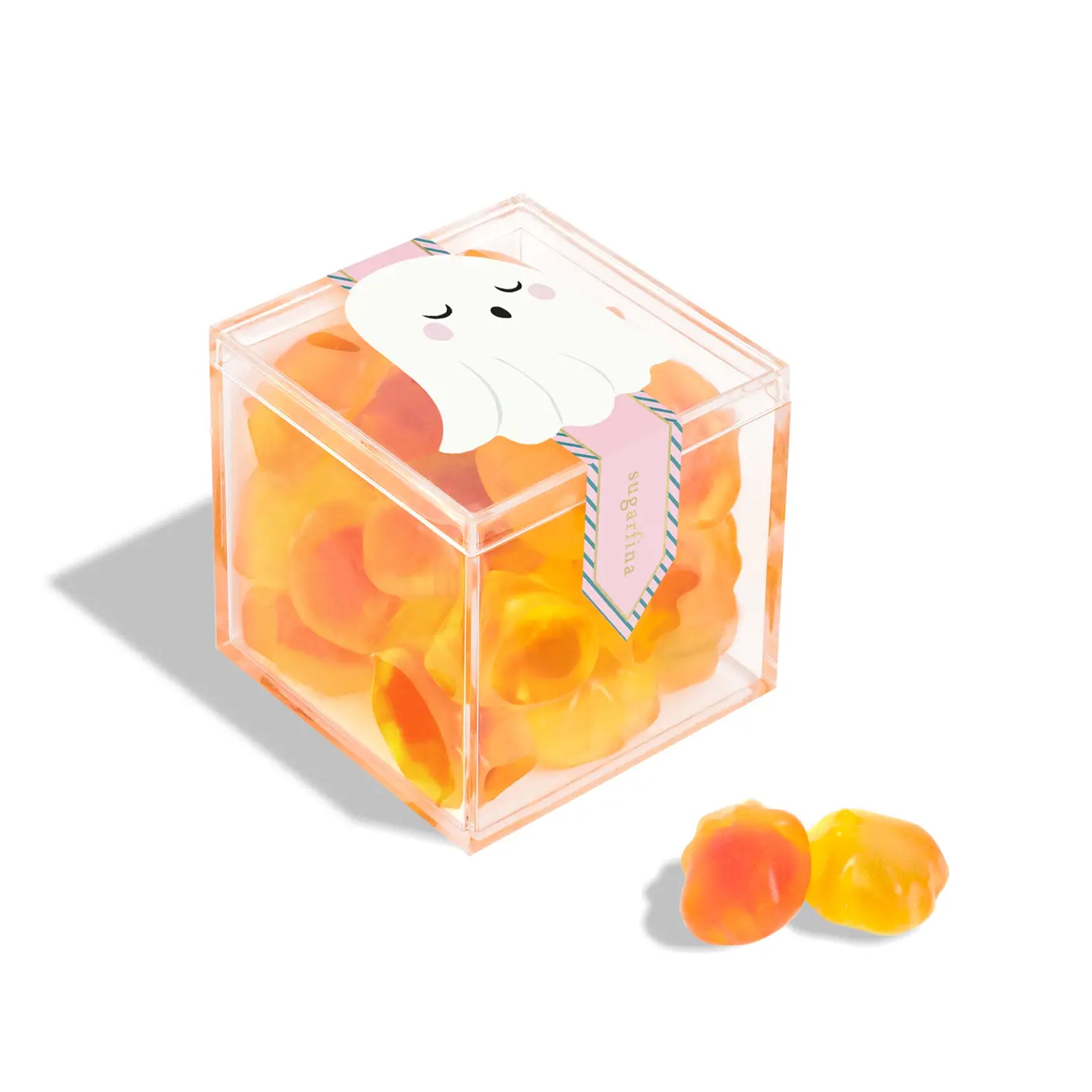 A clear acrylic box of orange and yellow ghost shaped gummy candies. 