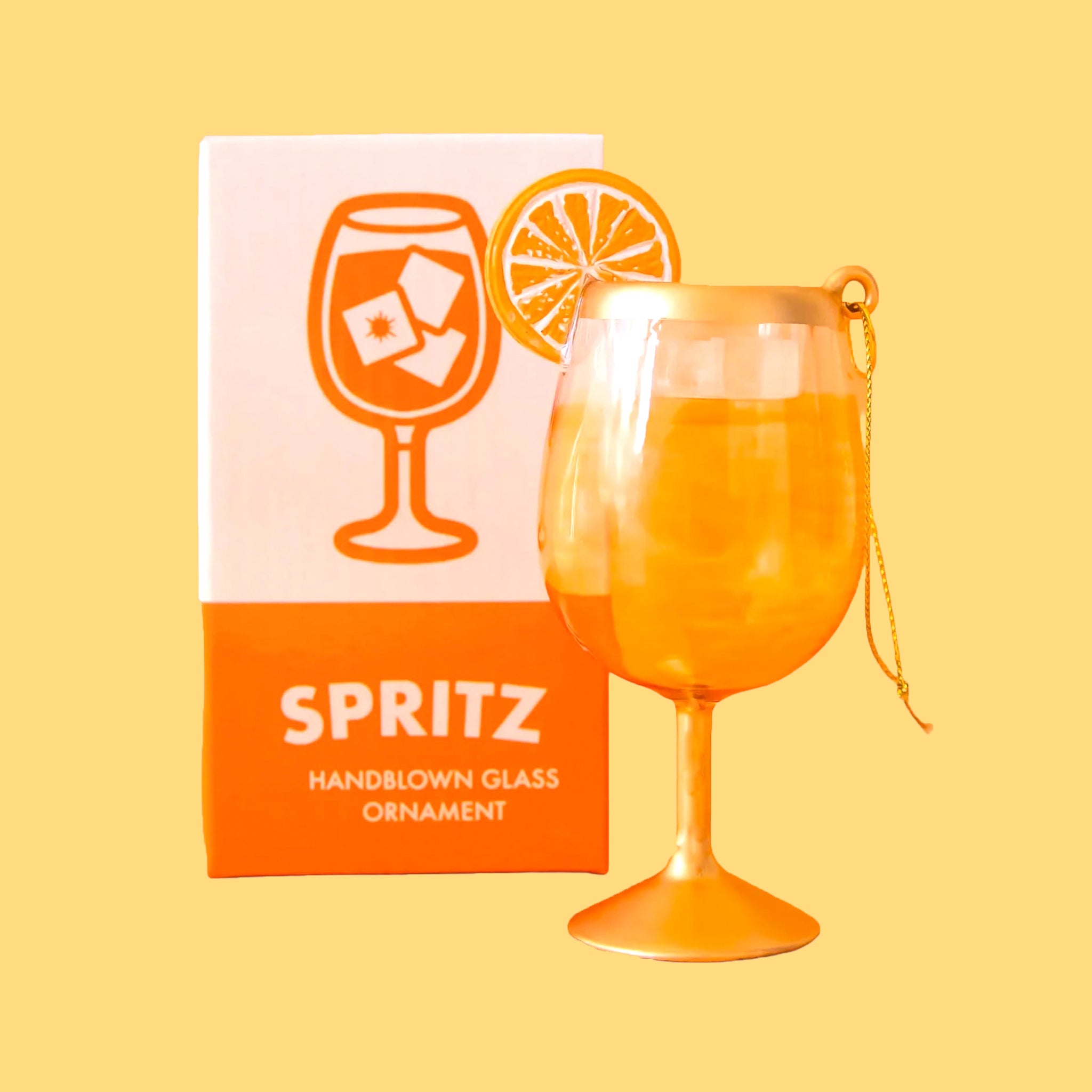 An orange and gold glass aperol spritz cocktail shaped ornament. 