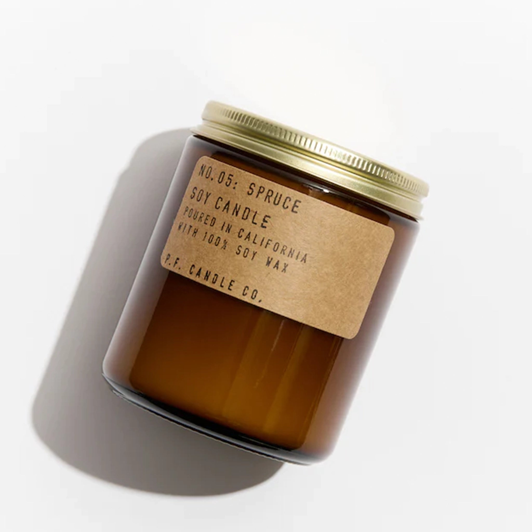 On a white background is an amber glass jar with a brown label that reads, "Soy Candle No. 05: Spruce". 