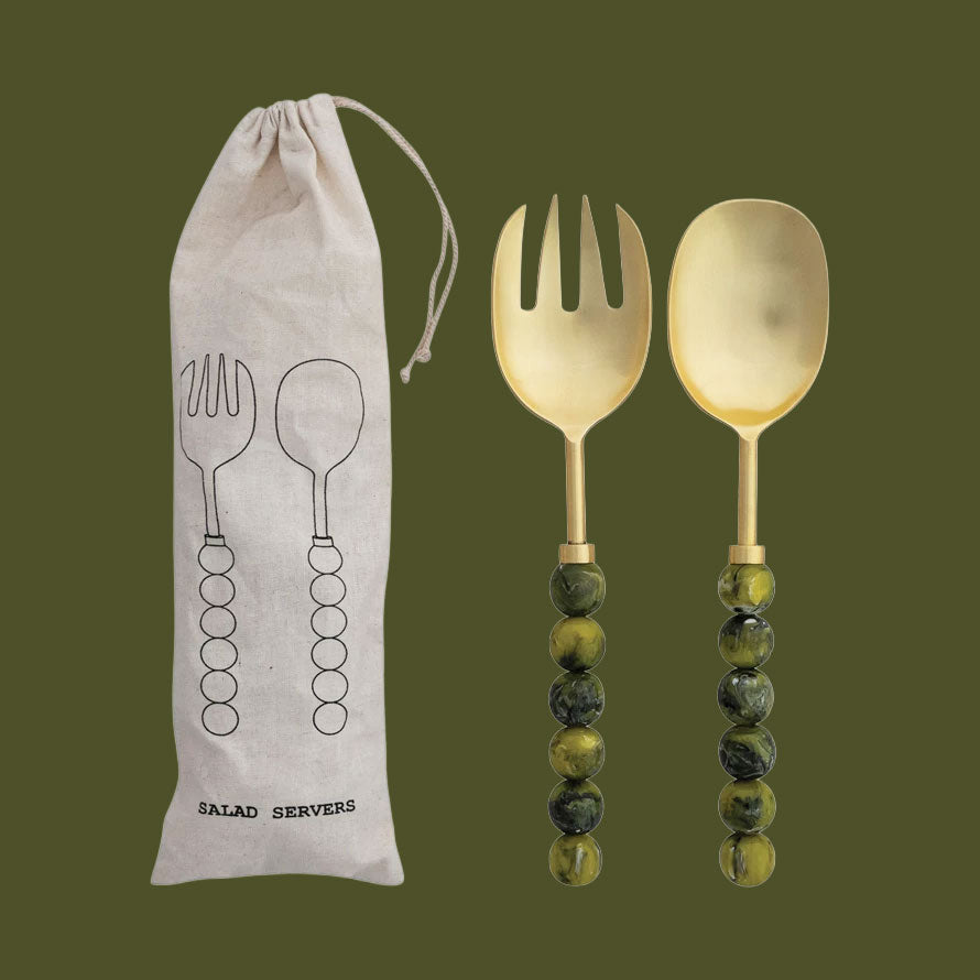 A pair of gold salad servers with green marble resin handles. 