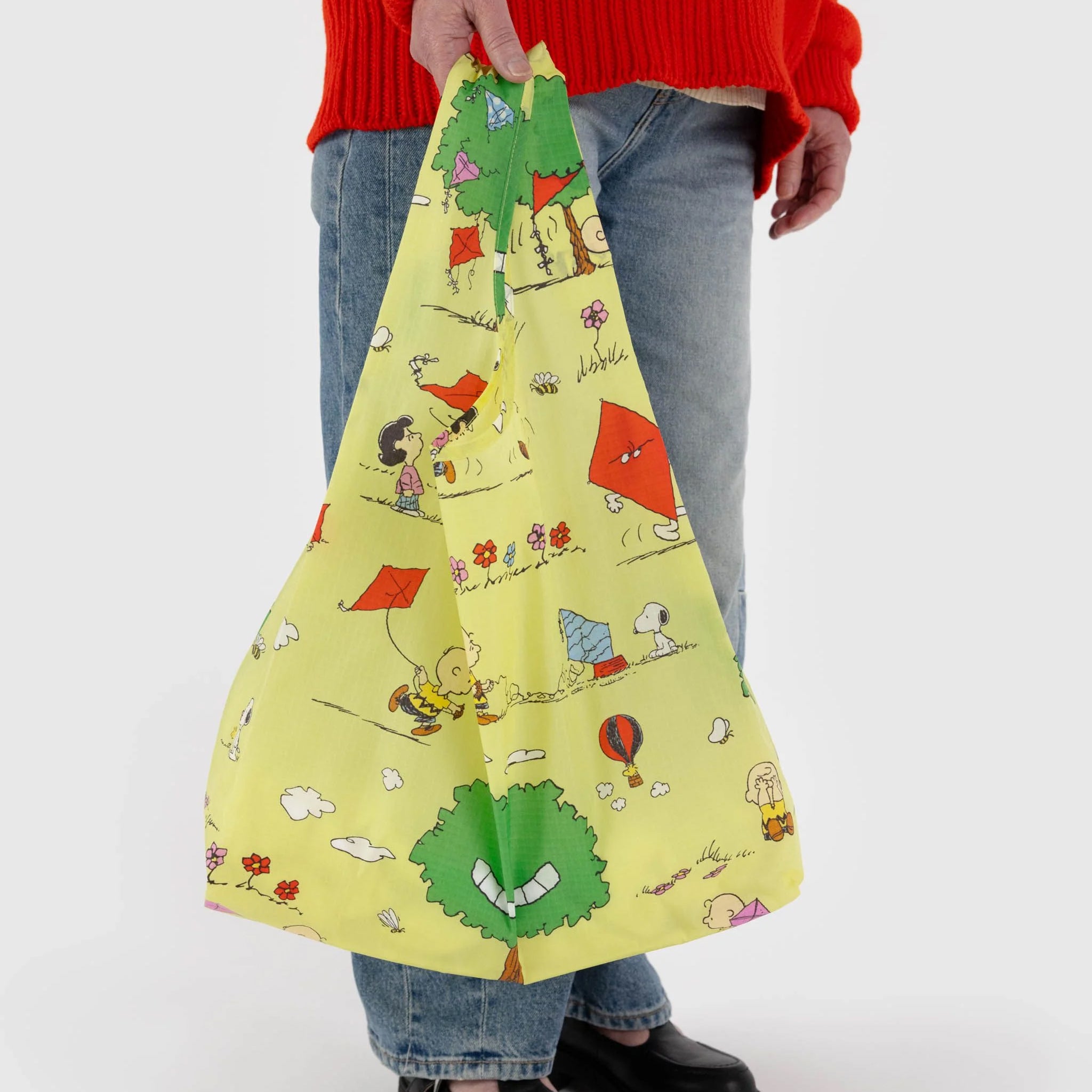 A yellow nylon reusable bag with a Charlie Brown kite eating tree print.