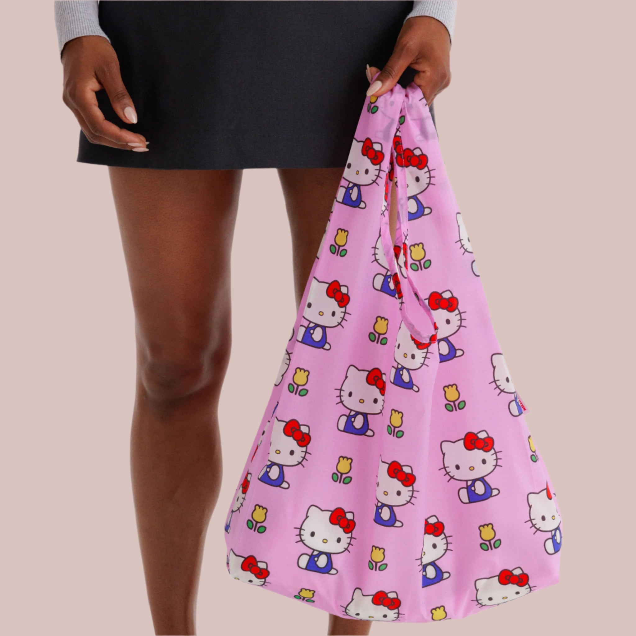A hot pink nylon, foldable tote bag with a Hello Kitty and floral print. 