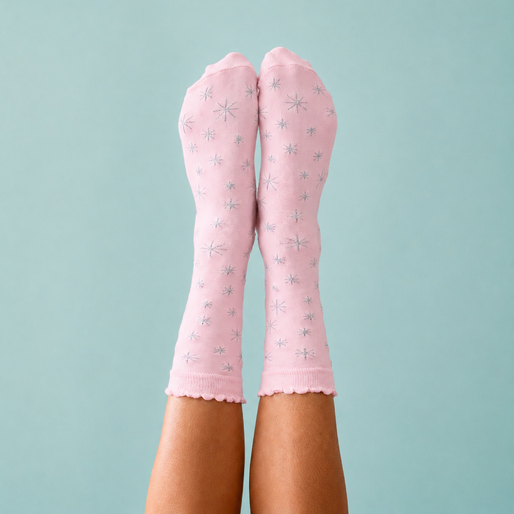 Feet in the air wearing pink socks with silver threaded stars on a blue background.