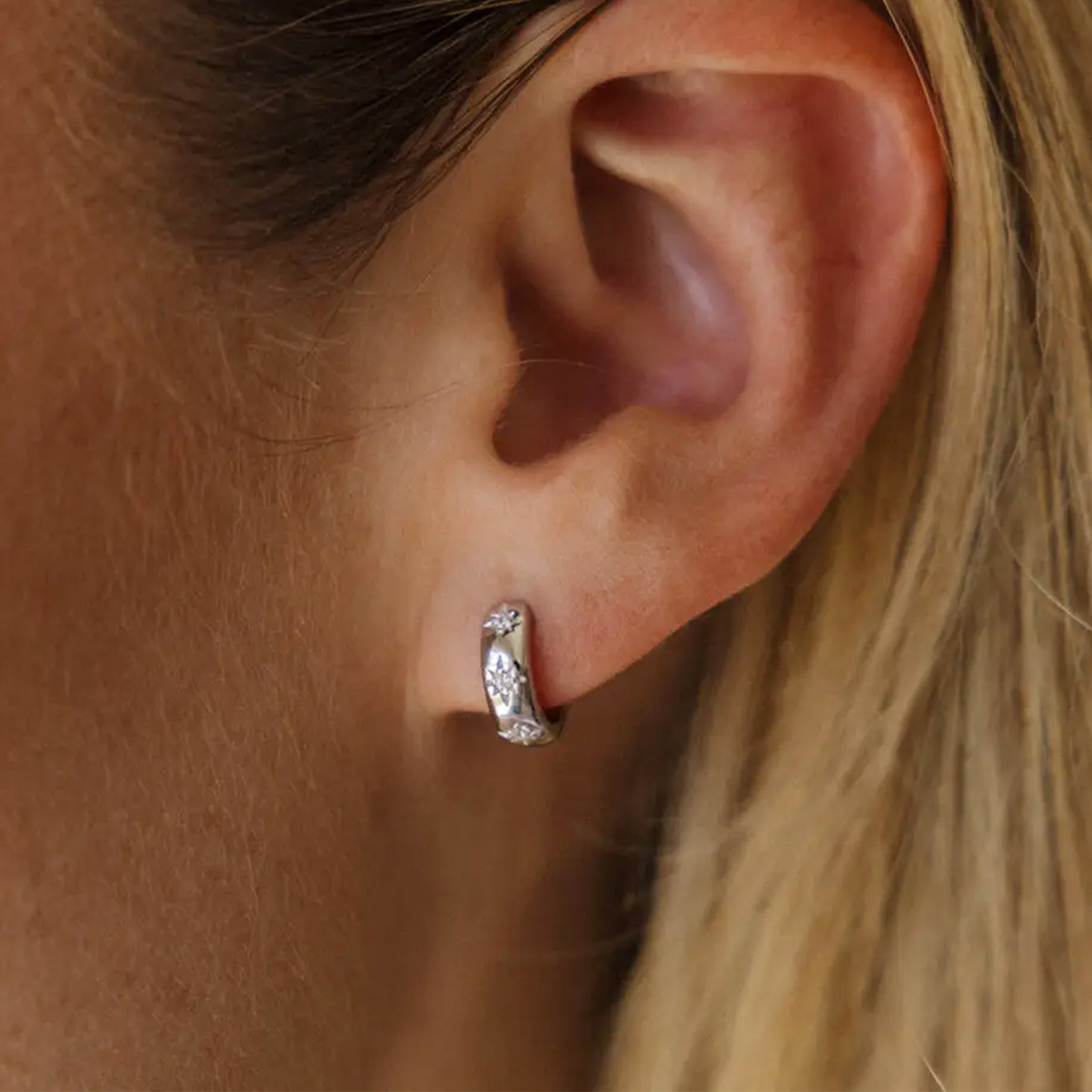 A silver pair of hoop earrings with star designs and cz stones. 