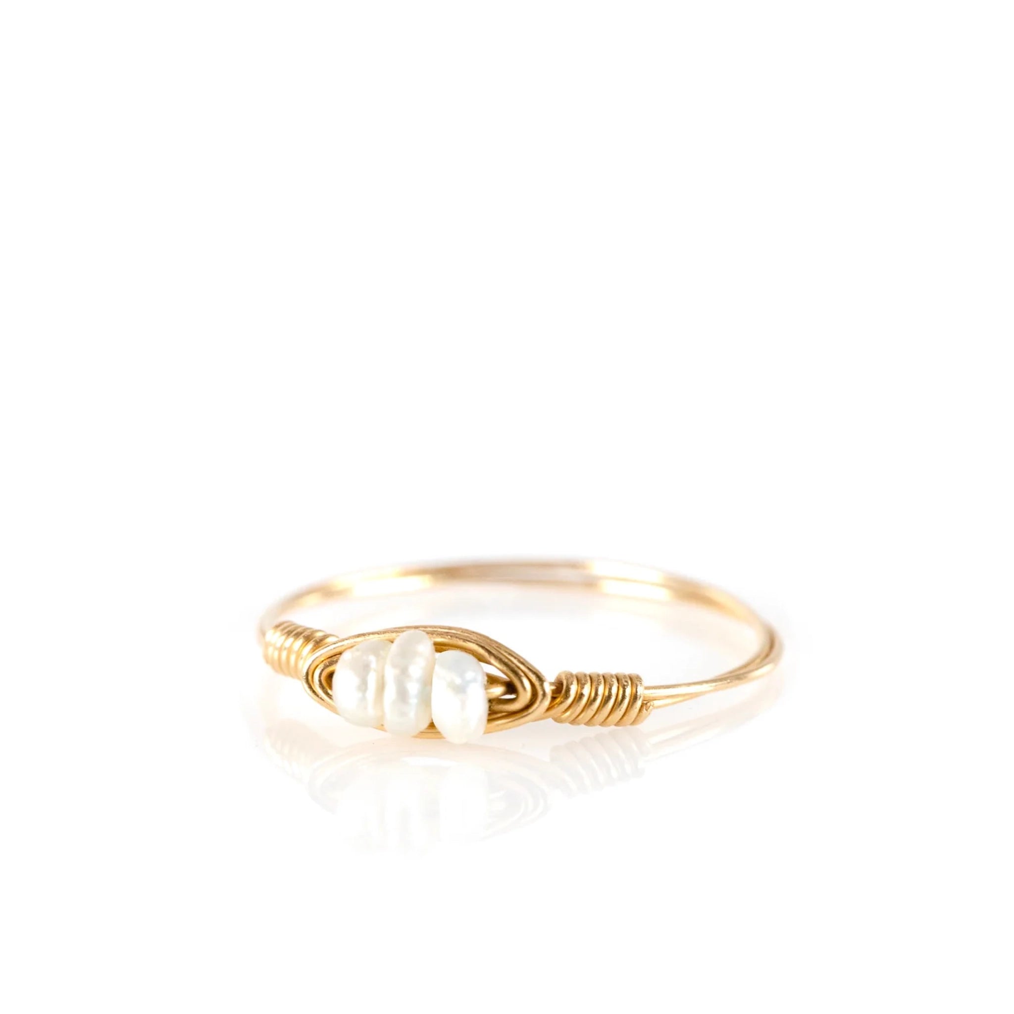The gold hand crafted statement ring with three small pearls in the center photographed on a white background. 