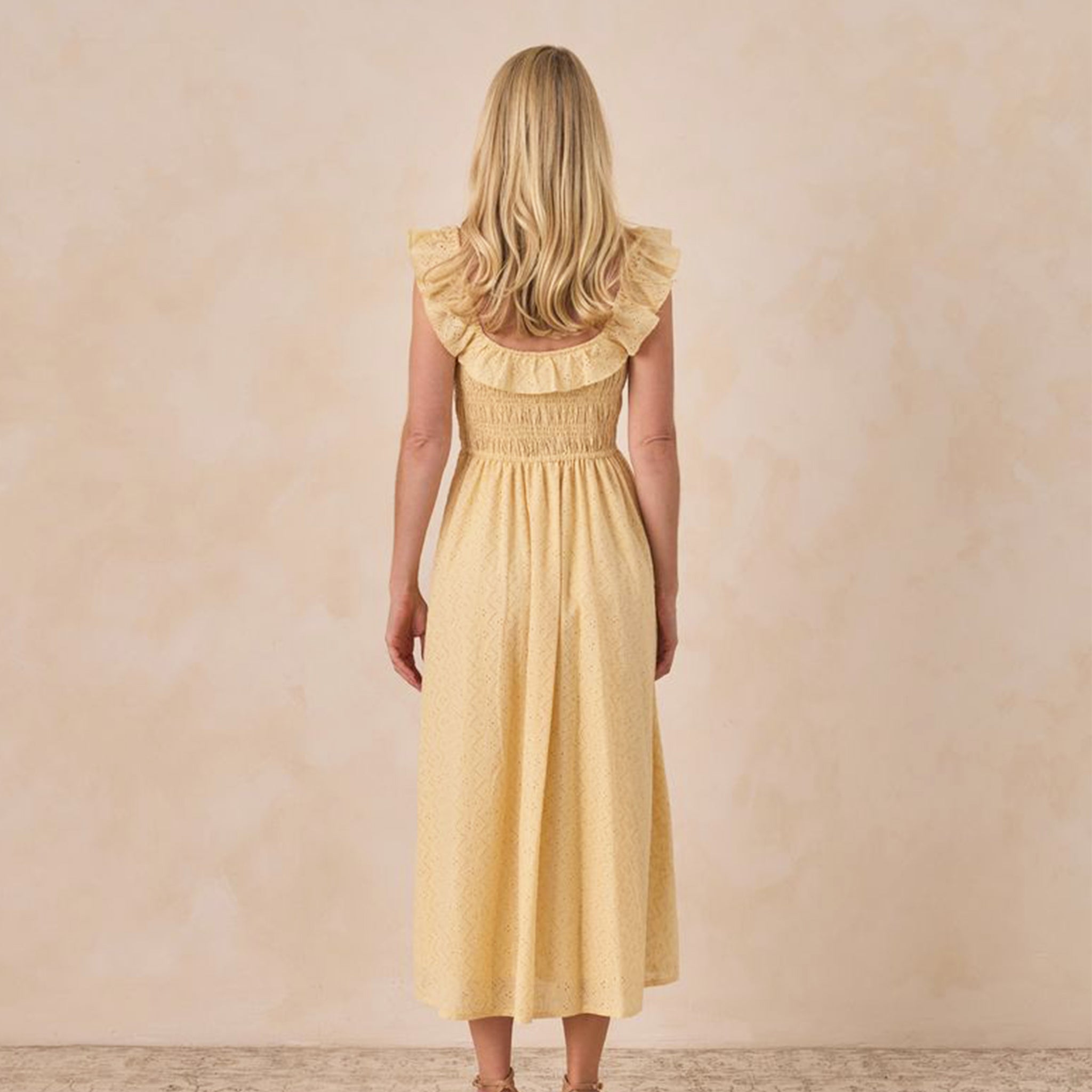 A yellow dress with a ruffle tank sleeve and neckline. 