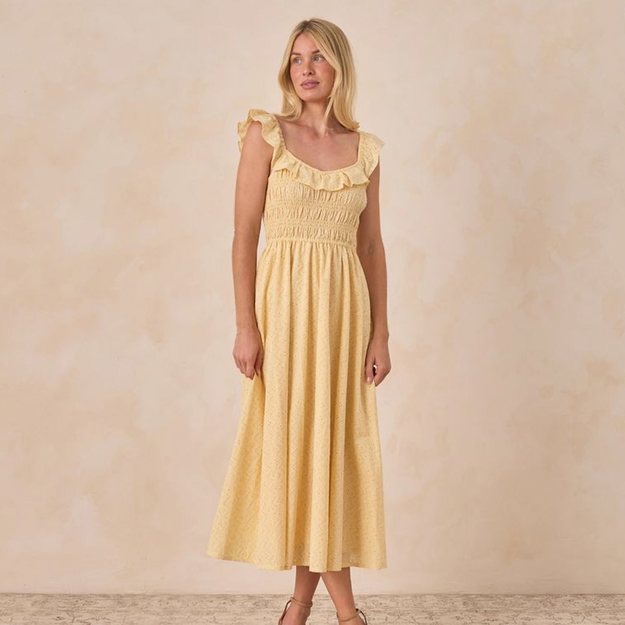A yellow dress with a ruffle tank sleeve and neckline. 