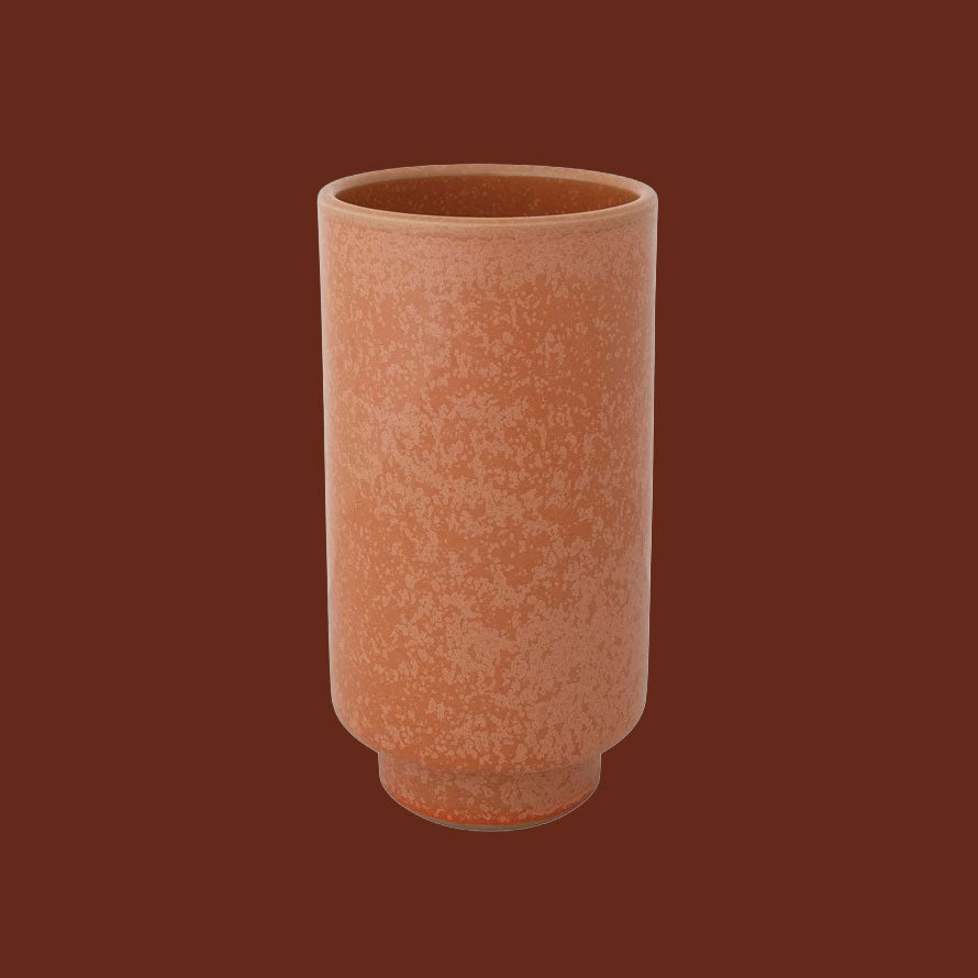 A coral colored ceramic vase. 