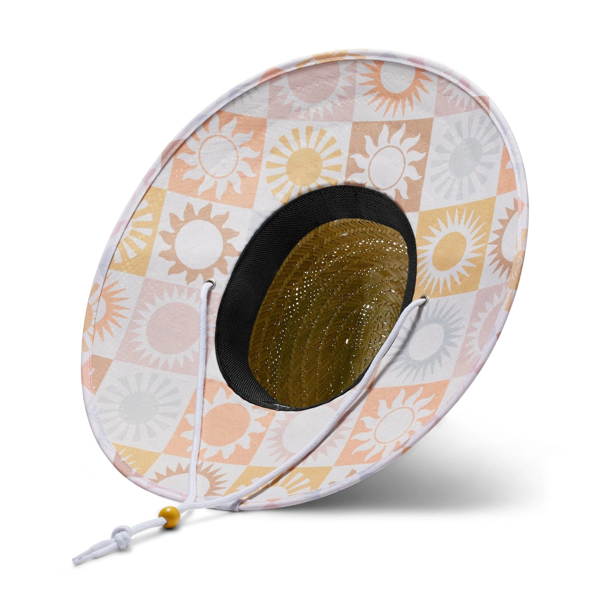 On a white background is a neutral colored straw sun hat with a neckstrap and a light pink and light orange sun design on the underside of the brim.