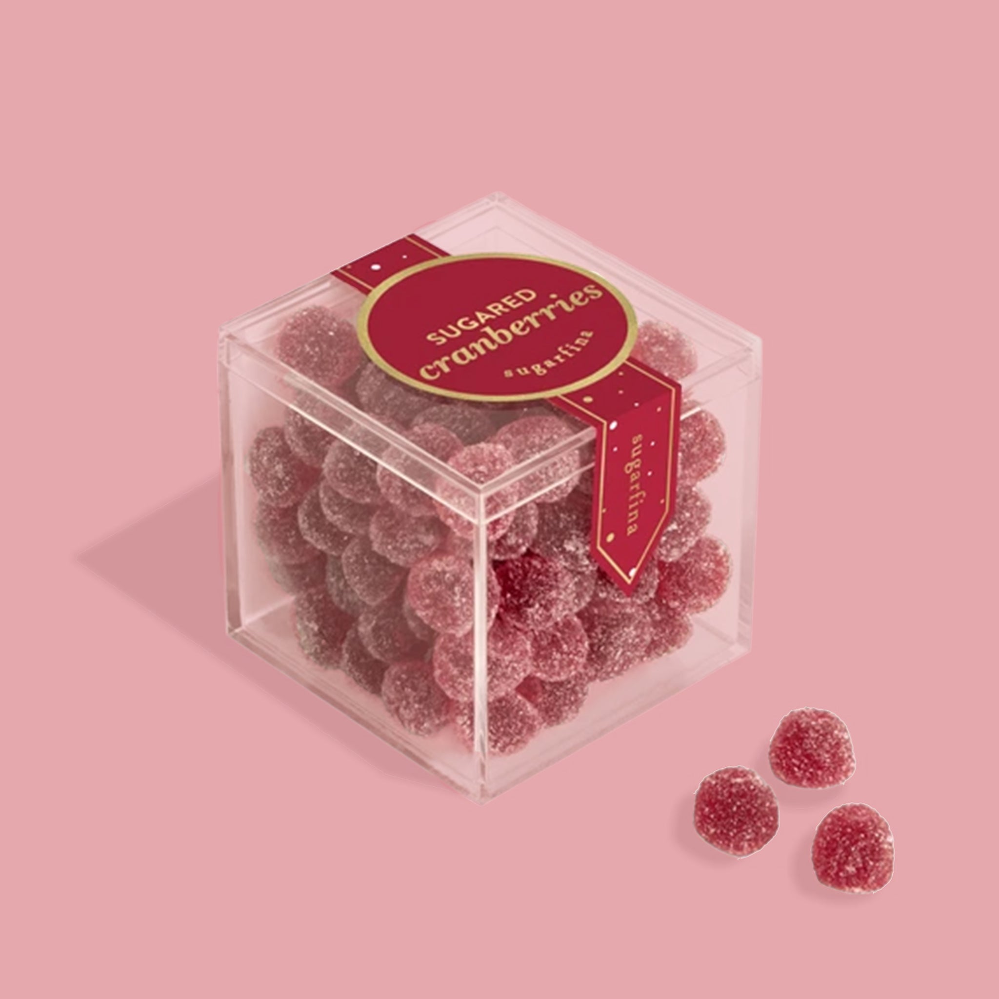 A clear acrylic box of cranberry shaped gummy candies covered with a sugar coating. The box reads, "sugared cranberries sugarfina". 