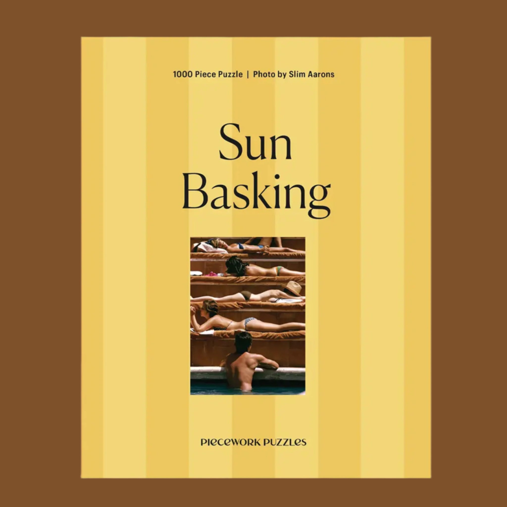 A yellow striped box with an image of people sun tanning and text that reads, &#39;Sun Basking Piecework Puzzles&#39;. 
