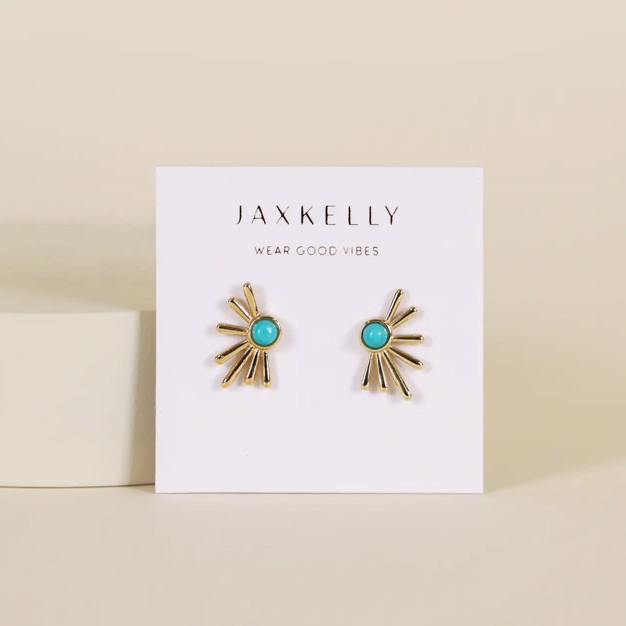 A pair of sunburst shape gold earrings with a turquoise stone in the center. 