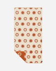 A cream and burnt orange towel with a sun design. 