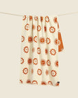 A cream and burnt orange towel with a sun design. 