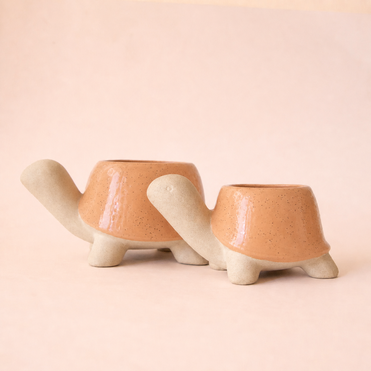 Two turtle shaped planters that are a peach color with speckled details.