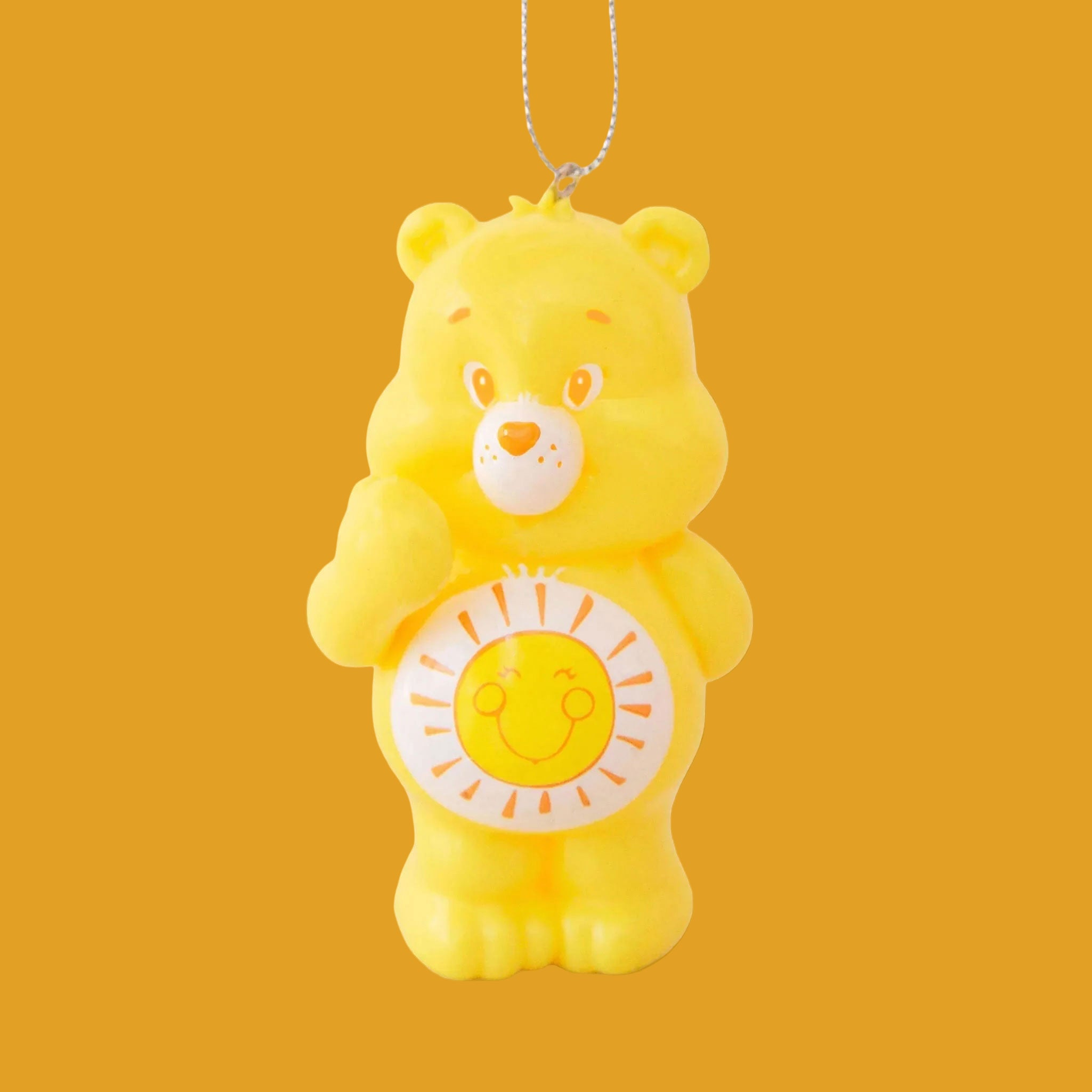 A yellow care bear shaped ornament with a yellow and orange smiling sun graphic on its stomach. 