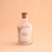 A glass jar filled with matches with a white arched label that reads, "Perfect Match" and a cork cap