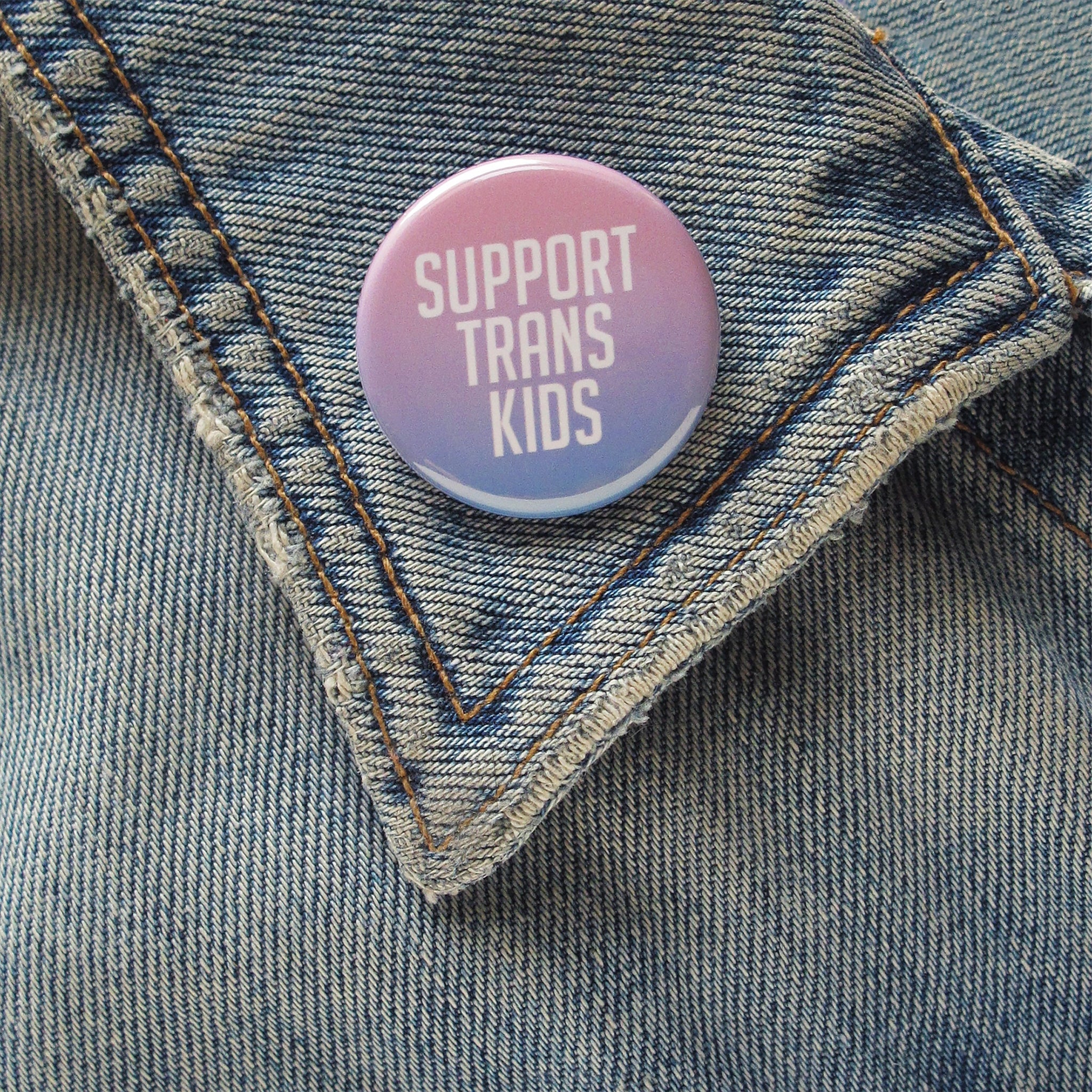Button with 'Support Trans Kids' text on a denim jacket