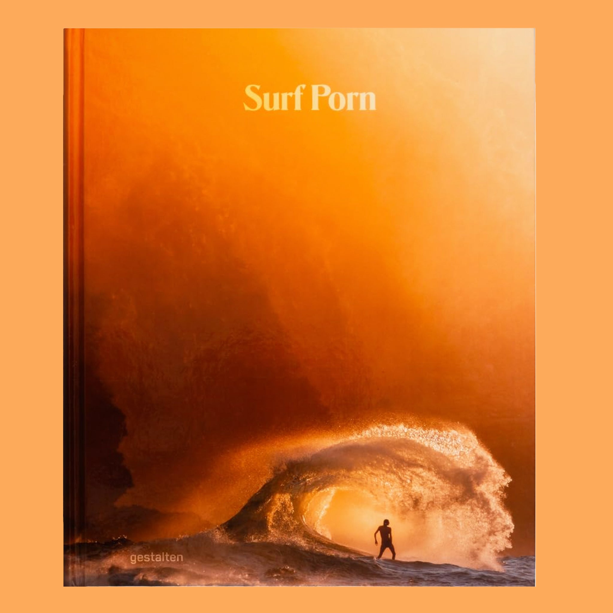 On an orange background is an orange book cover with a sunset and a wave with a surfer riding in the tunnel and text at the top that reads, "Surf Porn". 