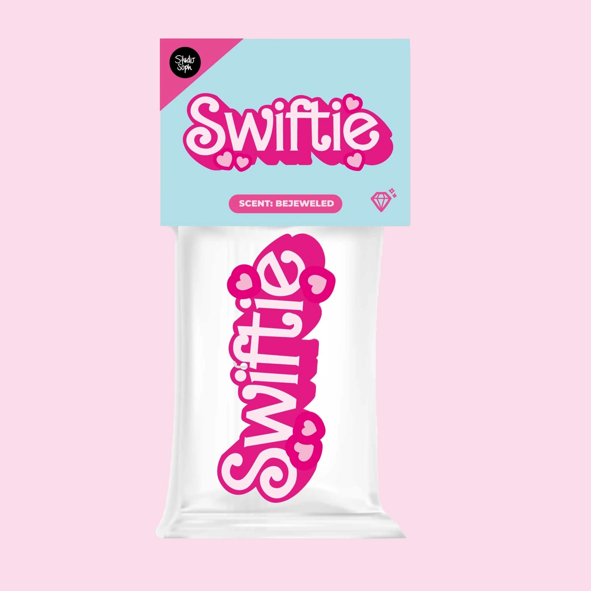 A pink and white air freshener in the plastic packaging that reads, &quot;Swiftie&quot;. 