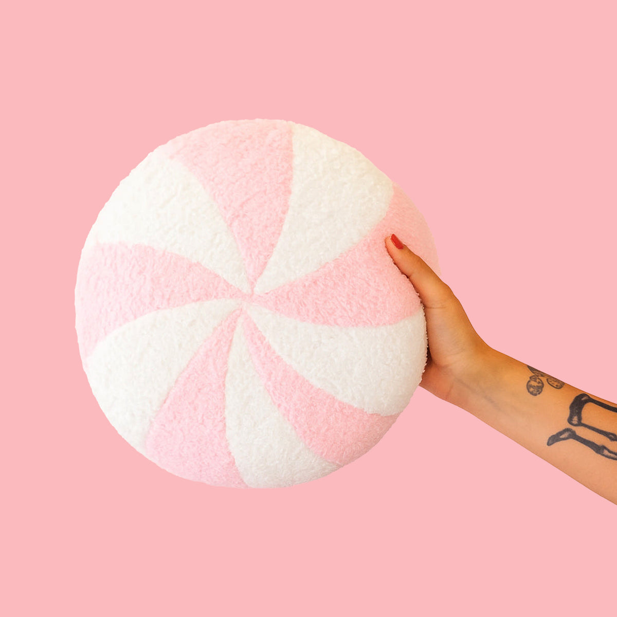 A round pink and white peppermint swirl candy shaped throw pillow. 